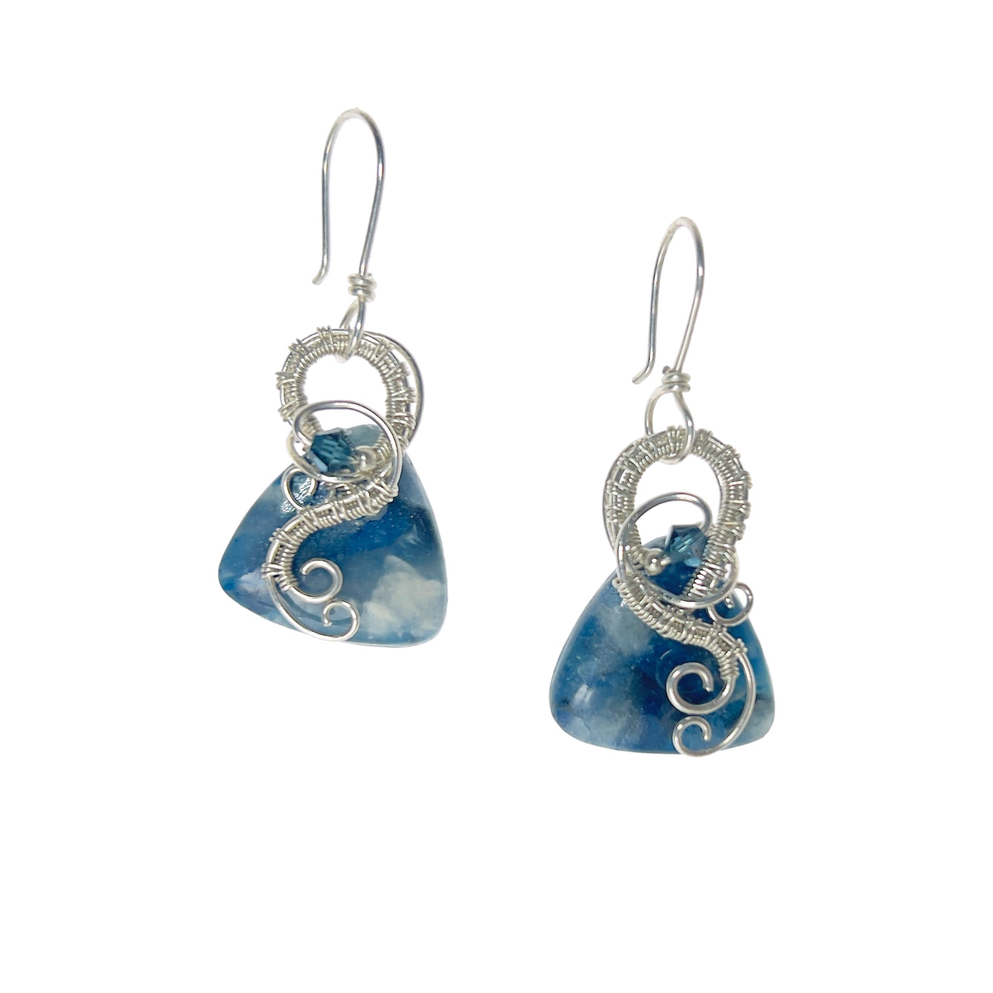 Dangle earrings with sterling silver loops and interlacing details curving down one side of a blue triangle-shaped stone, accented by a vintage blue Austrian crystal, a glass bead, and scrollwork.
