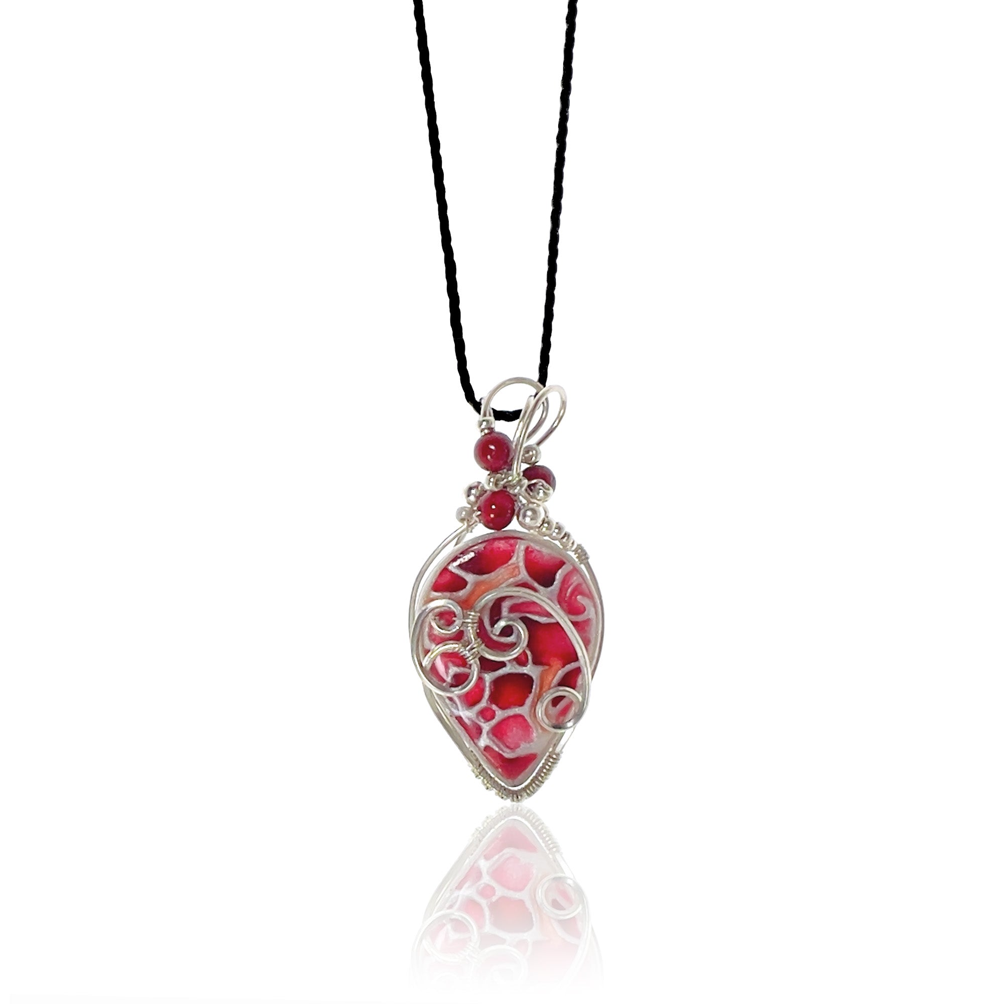 Drop-shaped pendant hand painted with rich reds accented with peach and sterling silver scrollwork, red riverstone beads with silver and glass beads at the top, hung from a silk cord.