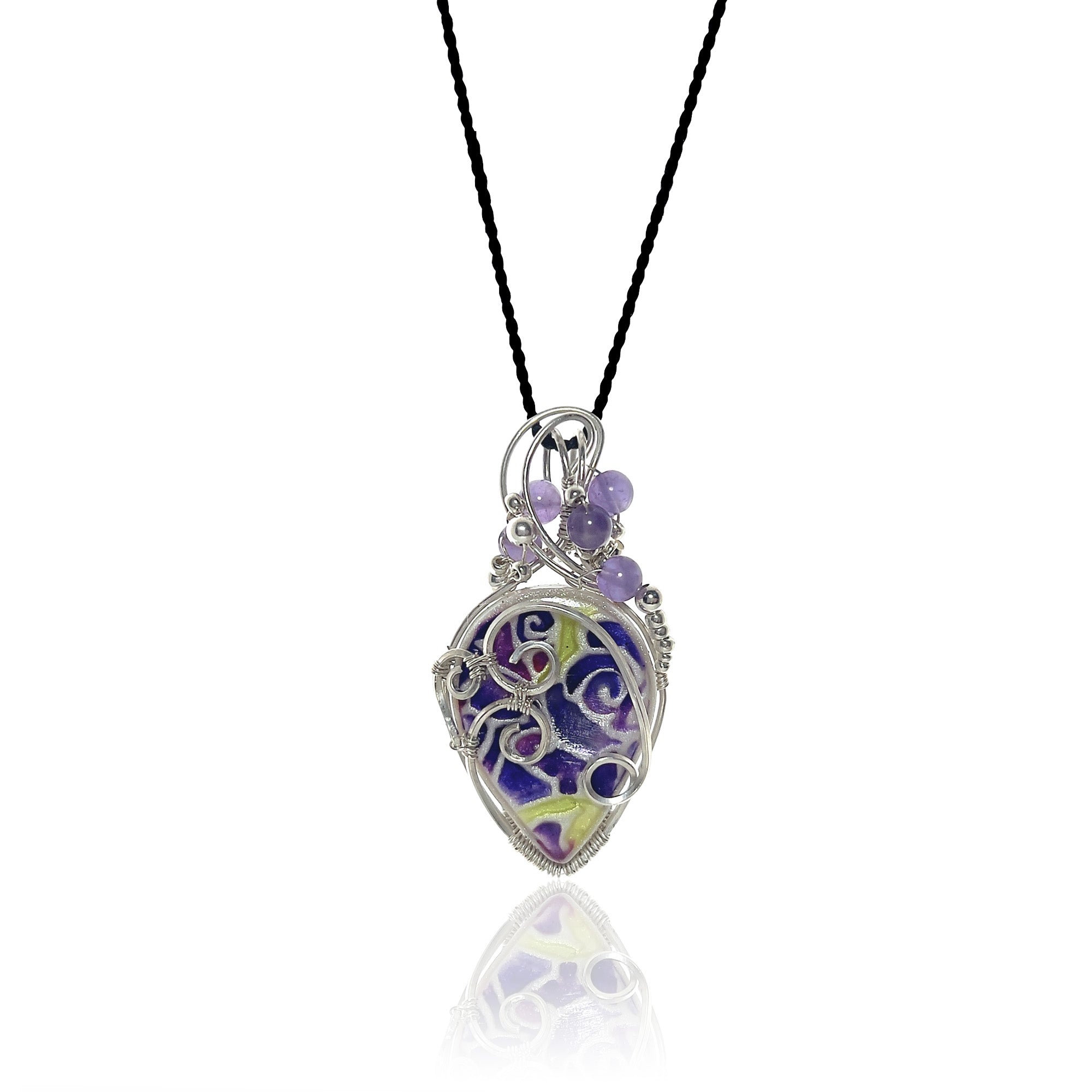 Drop-shaped original handcrafted stone pendant, hand painted with blues and accented with mauve; sterling silver scrollwork on the front, amethyst beads with silver and glass beads at the top, hung from a silk cord.