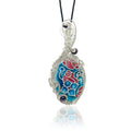 Pendant necklace with a floral face in shades of blue, teal, and deep mauve, accented by two rhodolite beads, hung on a black silk cord.