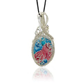 Hand-painted pendant necklace with an floral blue, teal and dark mauve design, framed by silver scrollwork and silver beads, suspended from a black cord.