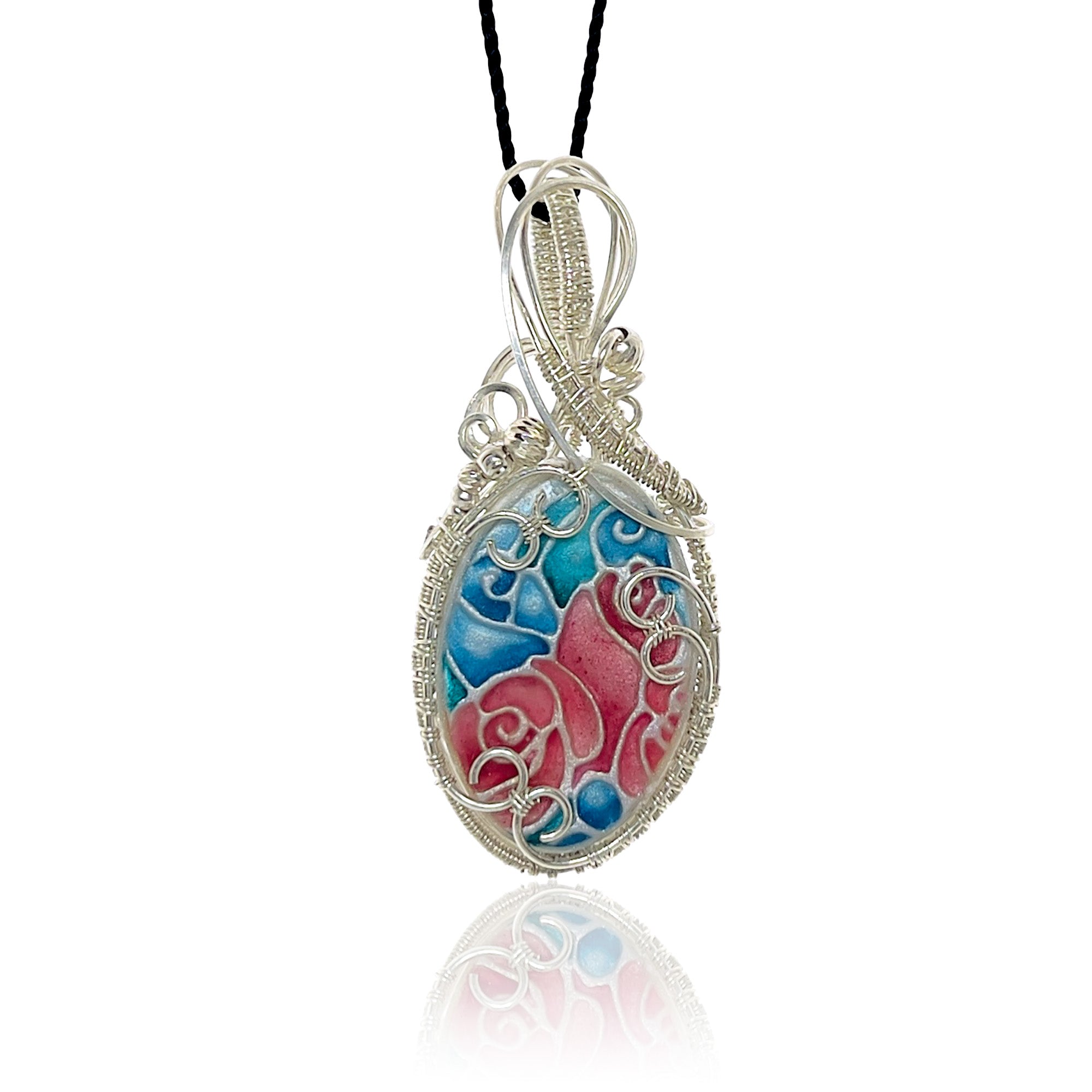 Hand-painted pendant necklace with an floral blue, teal and dark mauve design, framed by silver scrollwork and silver beads, suspended from a black cord.