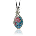 Sterling silver scrollwork pendant necklace with a hand-painted floral design in pink, teal and blue, hung from a black silk cord.