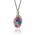 Pendant necklace with a hand-painted floral stone resembling cloisonne in pink, magenta, teal, and mint green, set in sterling silver with silver beads and one aquamarine bead, hung from a black silk cord.